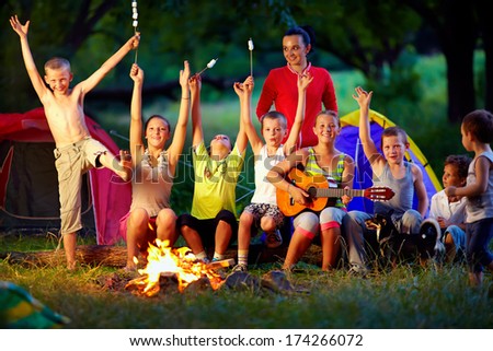 laughing kids friends having fun around campfire