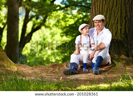 father and son sitting under an old tree