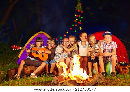 happy kids singing songs around camp fire