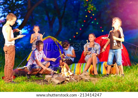 happy kids around bonfire in summer camp