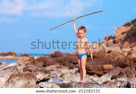 cute boy with bamboo spear pretends like he is aborigine on desert island
