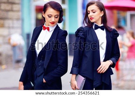 two gorgeous women posing in black suits