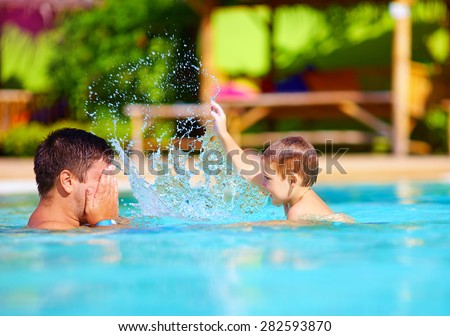 joyful father and son having fun in waterpark pool, summer holidays