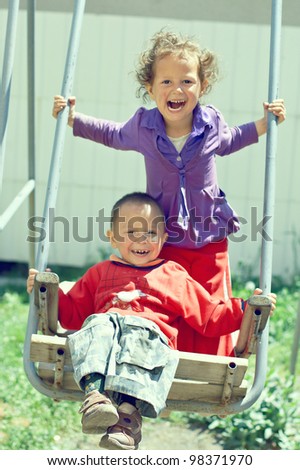 poor but happy little gypsy siblings in swing outdoor