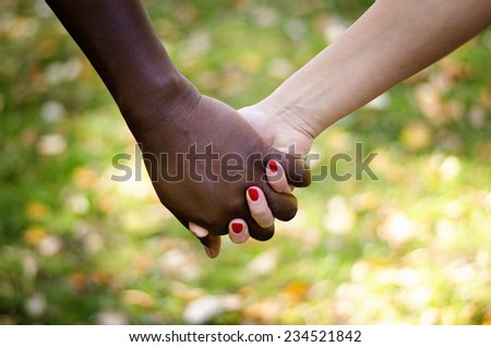 Close up on a mixed race couple holding hands in the park