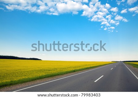 never ending highway through green fields and blue cloudy sky