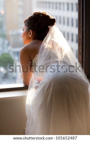 Beautiful Bride looking out a window in reflection of her new life