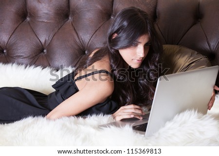 Gorgeous Brunette lying on a fur rug with a laptop