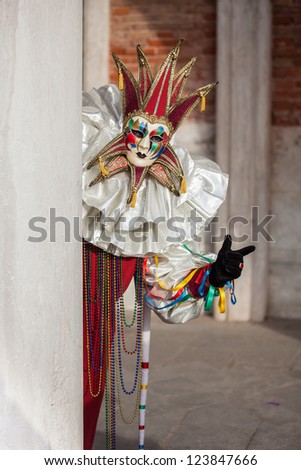 Beautiful Golden Venetian Carnival Masked man hiding by an Ancient pillar.