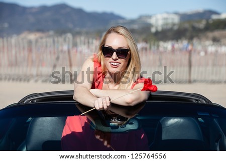 Pretty blonde woman behind in a sports car with a heart