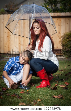 Mother and her son in the rain on a sunny day under an umbrella