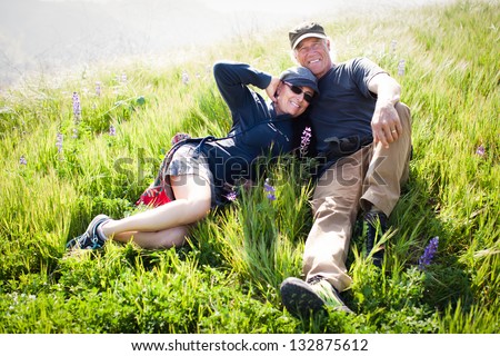Beautiful fit Middle aged couple lying in the tall grass and Wild Lupine