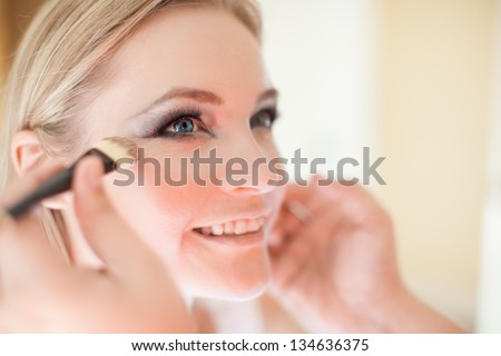 Young beautiful bride having wedding make-up by make-up artist