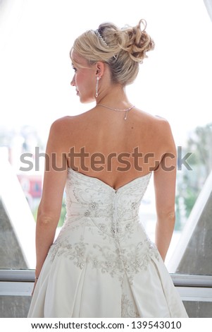 Elegant back view of a Beautiful blond bride in a modern glass hotel room penthouse suite