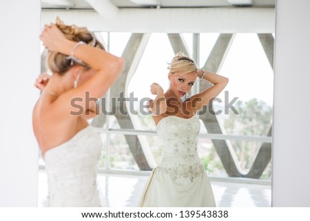 Elegant Reflection of a Beautiful blond bride in mirror in modern glass building penthouse