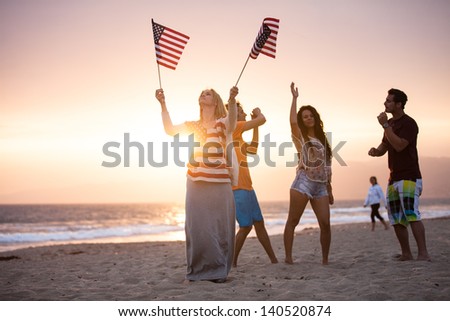 Group of Friends in their twenties dancing on the Beach at Sunset on 4th of July