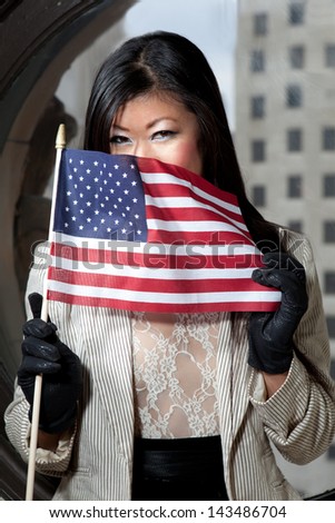 Asian woman holding an American Flag over her face in a lace top