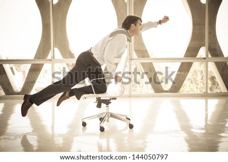 Good looking Business man Flying on a chair as if to be superman