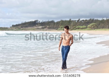 Cute young man in his twenties walking on the Kealia Beach in Kauai , Hawaii