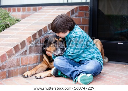 A 10 year old boy and his dog lying down on the sidewalkA 10 yeqr old boy and his dog sitting down on the sidewalk