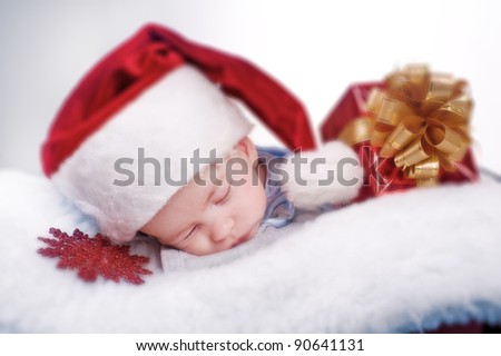 child baby in red Santa's hat sleeping on white blanket