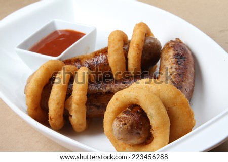spicy American grilled sausages served on a white plate with spicy sauces and delicious baked potatoes and crunchy onion rings ketchup  mustard