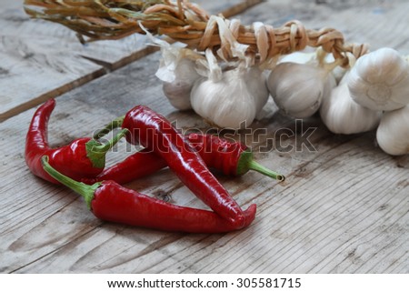 chili peppers and garlic - fresh organic red chili peppers and garlic clove in the domestic garden on a rustic wooden background