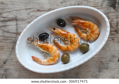 shrimp - prepared fresh seafood scampi and black olives and green olives with some olive oil on natural organic rustic wooden background