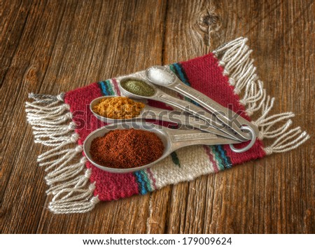 Selection of colorful spices in measuring spoons on an old worn wooden crate.