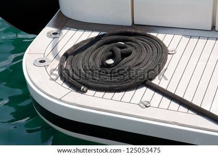 Black rope over a yacht deck made of white wood.