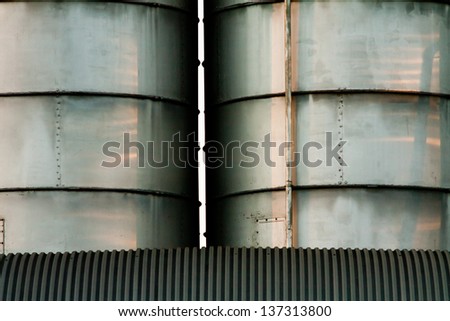 line of metal silos under a roof with radent sunlight with contrast and light reflex