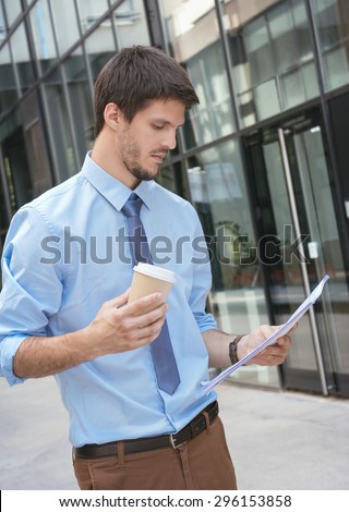 Young business man with a coffee holding files