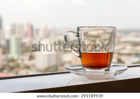 a glass with tea at the window with soft blur city view in background