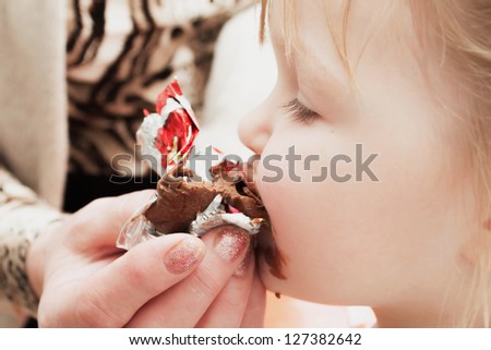 little girl eating chocolate candy. Pleasure.