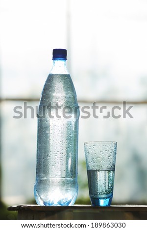 Blue glass of water and bottle with mineral water on the table