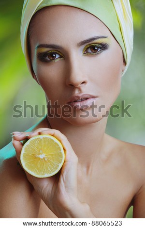 beautiful woman with lemon in yellow scarf on her head over nature background