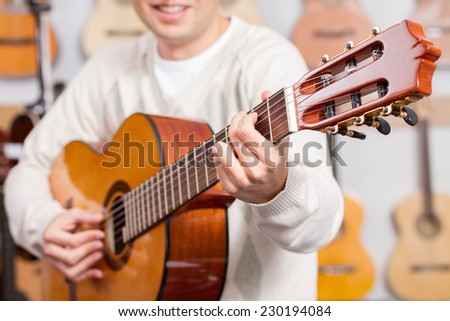 Close up of man playing a guitar with guitars background. Selective focus