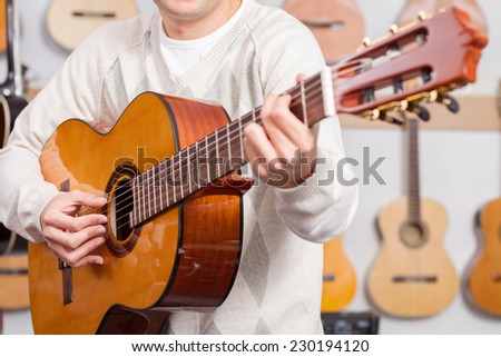 Close up of man playing a guitar with guitars background. Selective focus