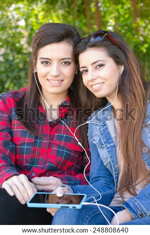 Girls smiling while listen music and share earphones