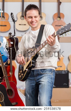 Man happy playing electric guitar in music shop