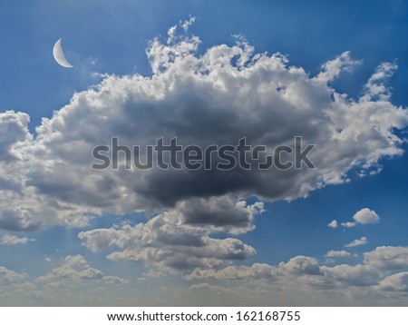 Unusual dramatic clouds against bright blue sky, with a crescent moon