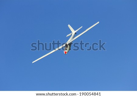 white sail-plane dive flight against blue sky