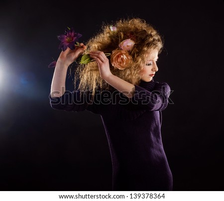 beautiful girl with curly hair and flower on black background