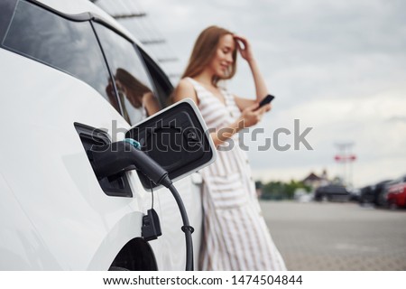 Similar – Image, Stock Photo An elegant woman charging an electric car in urban settings