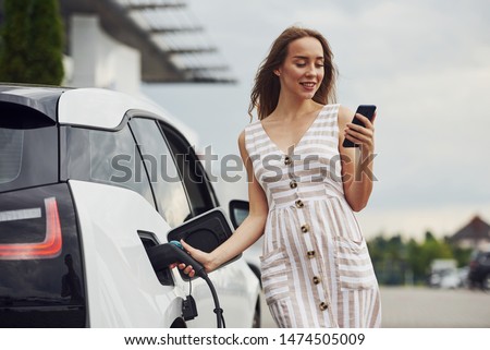 Similar – Image, Stock Photo An elegant woman charging an electric car in urban settings