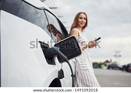 Similar – Image, Stock Photo An elegant woman charging an electric car in urban settings