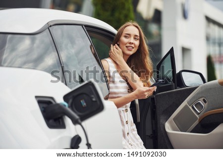 Image, Stock Photo An elegant woman charging an electric car in urban settings