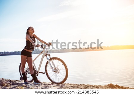 Charming girl in a sports bike on sunset near the water