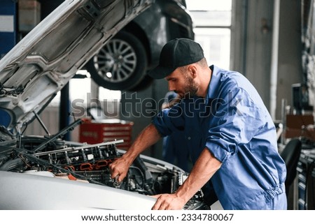 Foto Bild Automechaniker bei der Arbeit an einem Automotor in einer Autowerkstatt. Reparatur Service. authentische Nahaufnahme Schuss