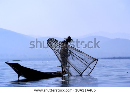 Fisherman on Inle Lake makes a living by using a coop-like trap with net to catch fish